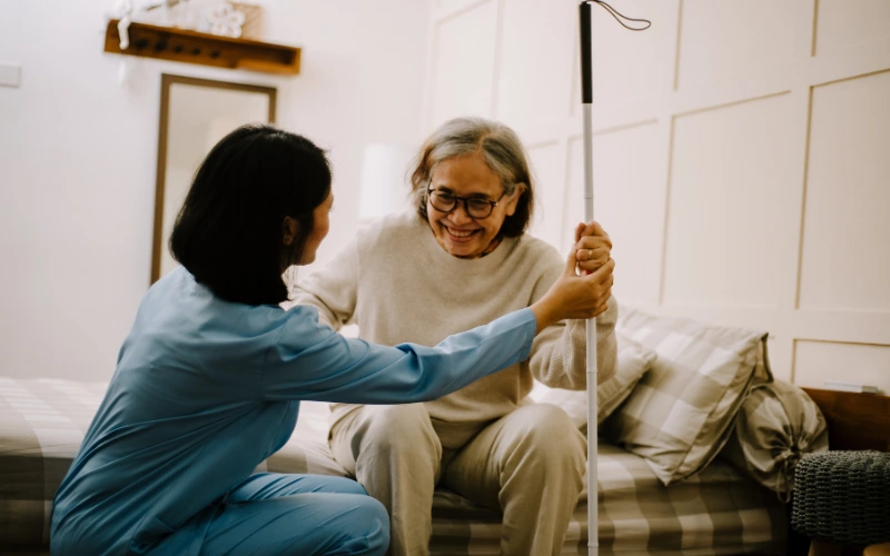 A nurse helping an older lady get out of bed